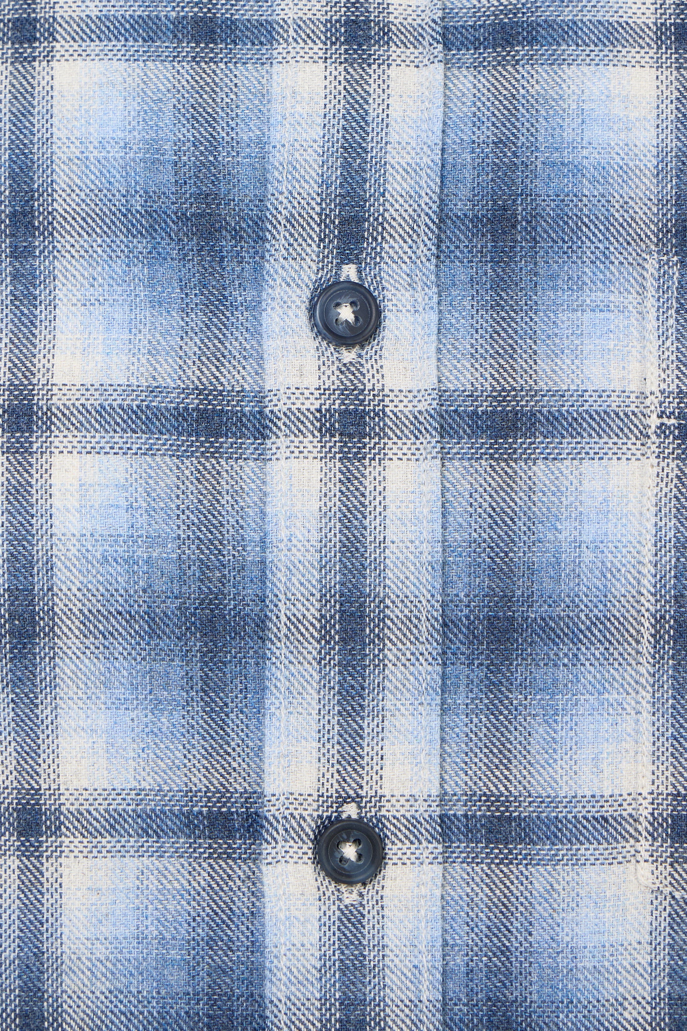 Close-up of a blue and white plaid shirt fabric with buttons.