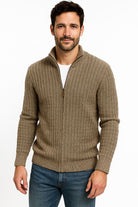 Man wearing a brown zip-up sweater and blue jeans on a white background