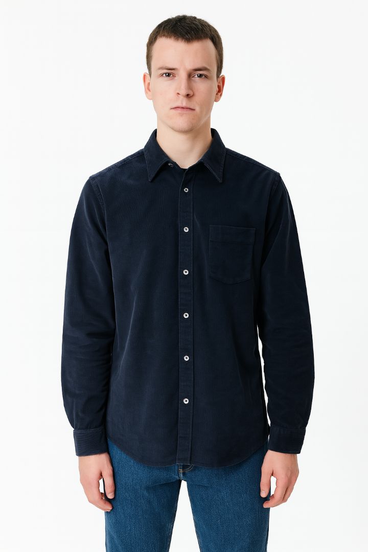 Man wearing a dark blue button-up shirt and jeans on a white background