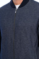 Close-up of a dark gray zip-up jacket with a white shirt underneath.
