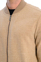 Close-up of a beige bomber jacket with a zipper on a white background