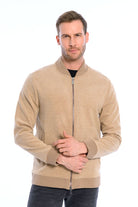 Man wearing a beige zip-up sweater on a white background