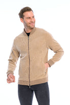 Man wearing a beige zip-up sweater on a white background